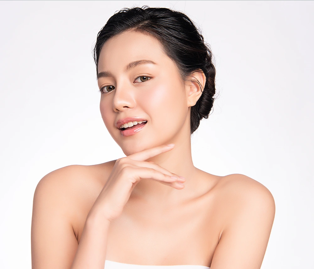 Woman with dark hair pulled back looking directly ahead with radiant, hydradated complexion