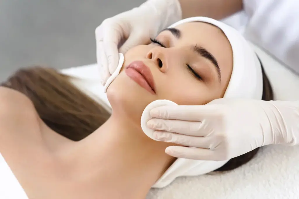 Aesthetician using soft sponges to cleanse a client's face during a custom facial