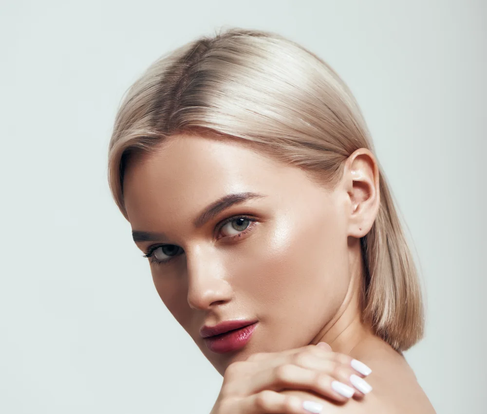 Blonde woman looking over her shoulder showcasing youthful facial volume after Juvelook.