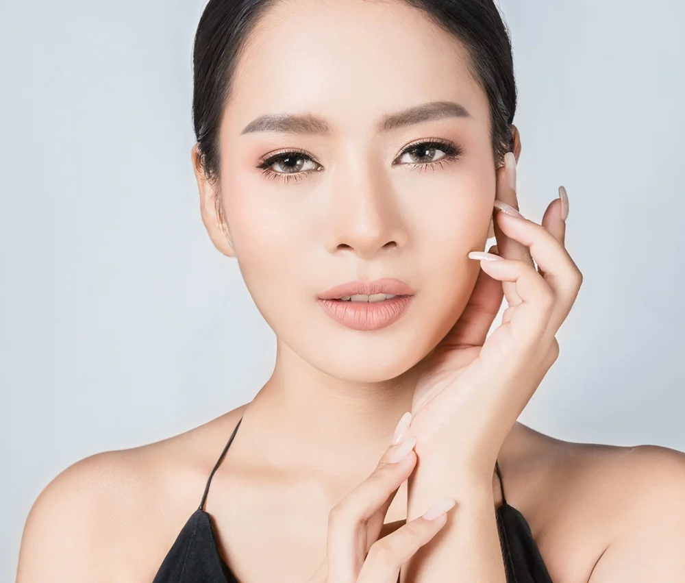 Woman with dark hair touching her cheek, showcasing clear skin tone post dark spot removal