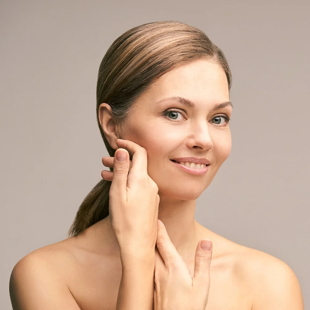 Close-up of a woman touching her cheek to demonstrate smooth skin after spot removal